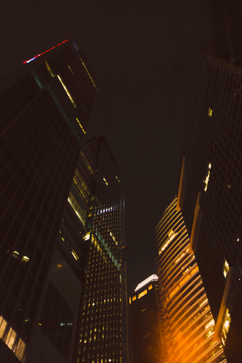 A nighttime cityscape featuring several tall skyscrapers illuminated against a dark sky.