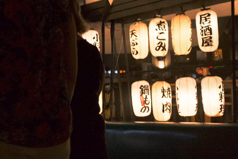 A person standing in front of a restaurant with traditional lanterns.