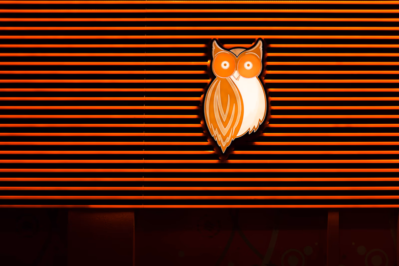 A stylized illustration of an owl set against a background of horizontal orange stripes.
