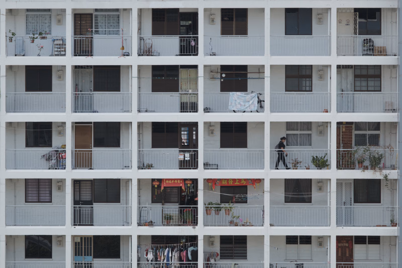 A large, multi-story apartment building with numerous balconies is shown in an urban setting.
