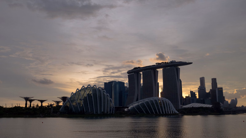 A panoramic view of the Singapore skyline at dusk, featuring the Marina Bay Sands hotel and the ArtScience Museum.