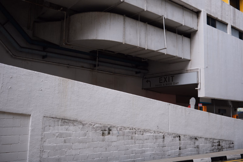 A white concrete structure features an exit sign that reads "EXIT HAVE A NICE DAY" mounted beneath an overhang.