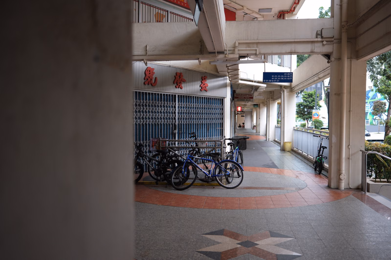 Several bicycles are parked near a covered walkway entrance with Chinese characters visible above the gate.