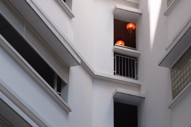 A white building facade features a small window decorated with red Chinese lanterns hanging inside.