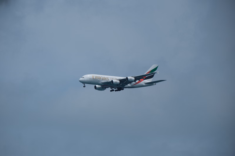 An Emirates airplane is seen taking off against a cloudy, overcast sky.