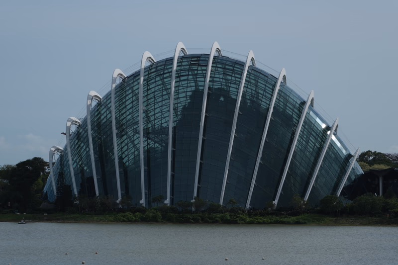 A photo of a modern, glass-covered building with a unique architectural design, taken near Marina Bay in Singapore.