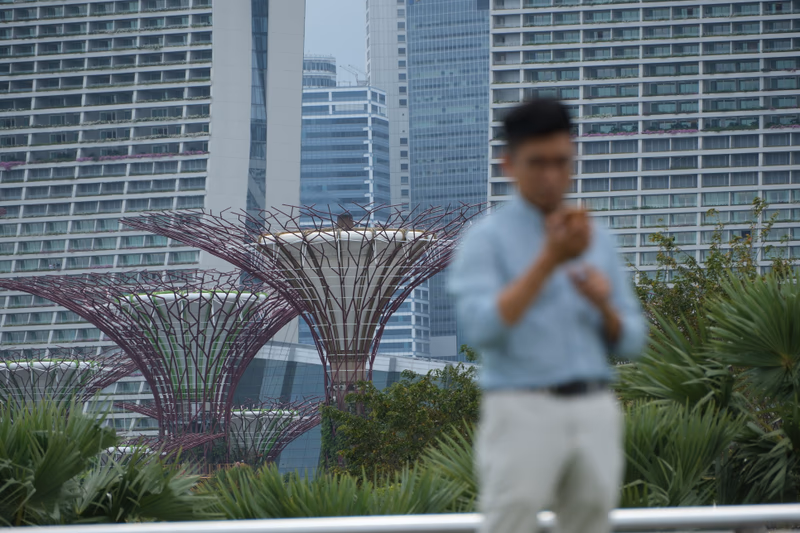 A man standing in front of a modern cityscape with distinctive structures in the background.