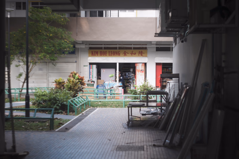A photo of a small garden area with a sign that reads 'Lavender, None, Singapore' and a building in the background.