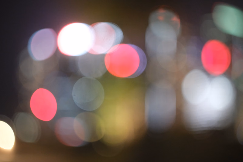A blurred background of colorful bokeh lights at night, suggesting a city or urban setting.
