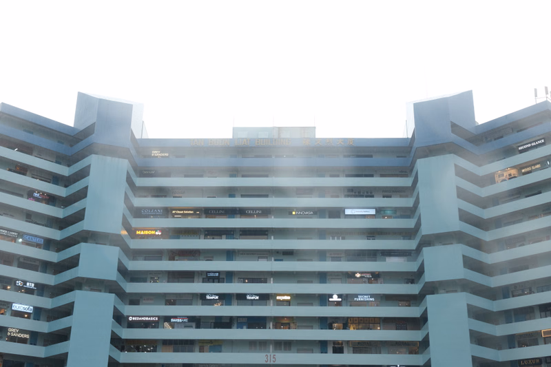 A large, modern commercial building with multiple floors features various retail signs, including "MAISON" and "CELLINI", and the address "315".