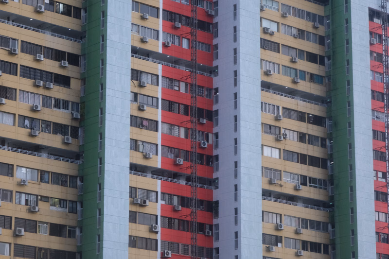 A row of tall, multi-story apartment buildings with varying facade colors, including white, gray, and red sections.