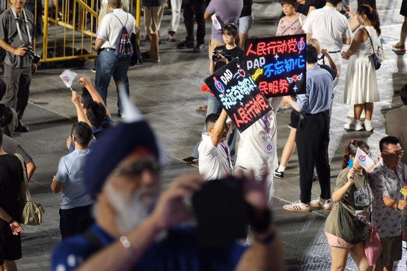 A group of protestors holding signs in a crowded outdoor street demonstration, with one sign clearly reading "DAD" and Chinese characters.