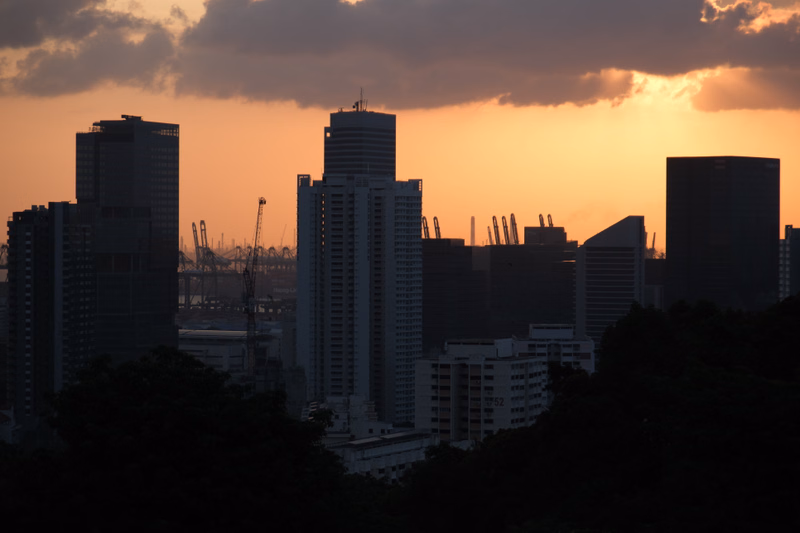 A cityscape of tall buildings silhouetted against a dramatic orange and purple sunset sky.