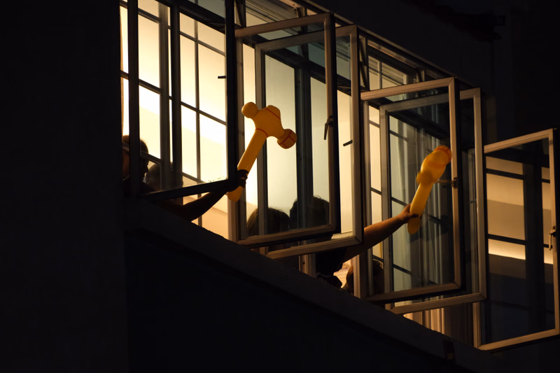 Several wooden toy hands are visible through large windows, illuminated by bright sunlight.
