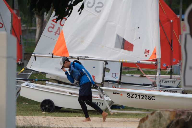 A person is walking near a sailboat.