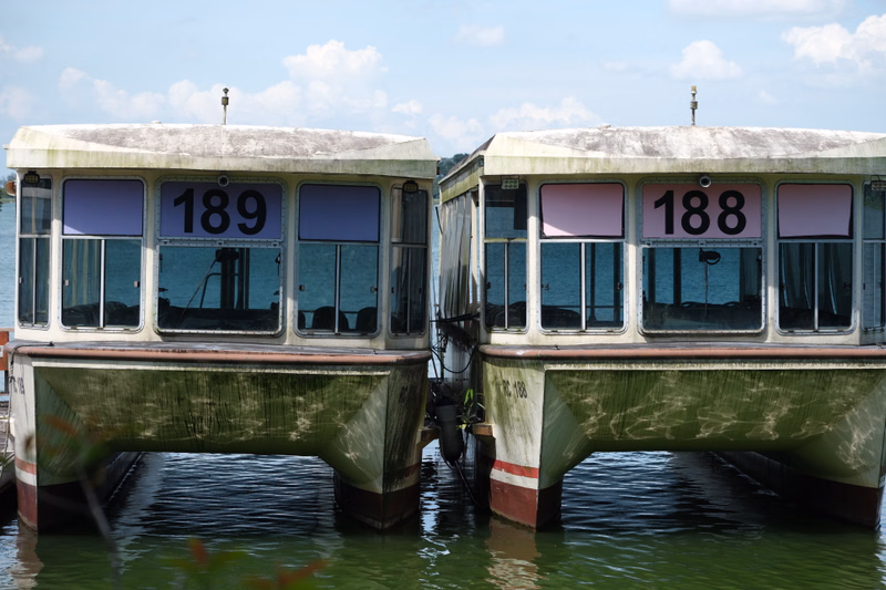 Two white and green houseboats are moored on the water, with one displaying the number "189" and the other "188".