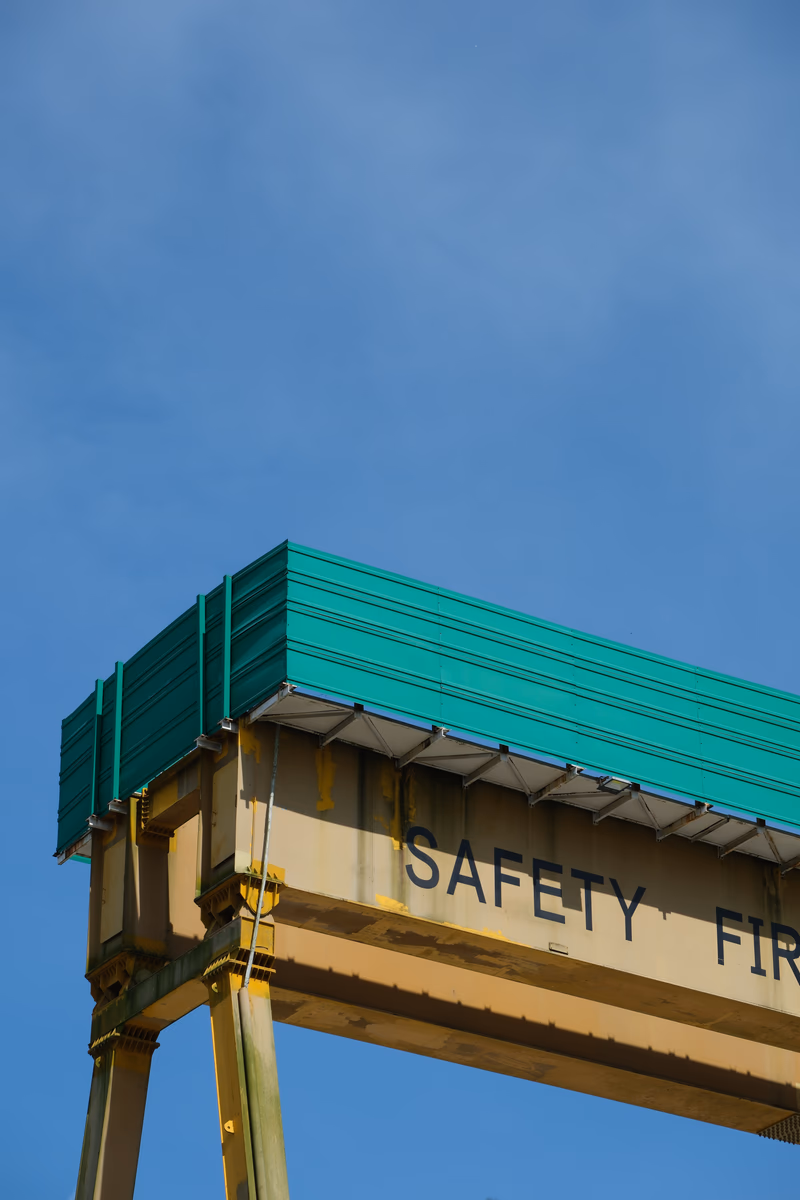 A crane with a safety sign and a building in the background