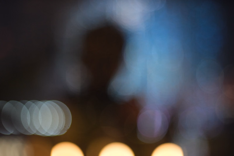 A heavily blurred photograph featuring bright, circular bokeh lights against a dark background.