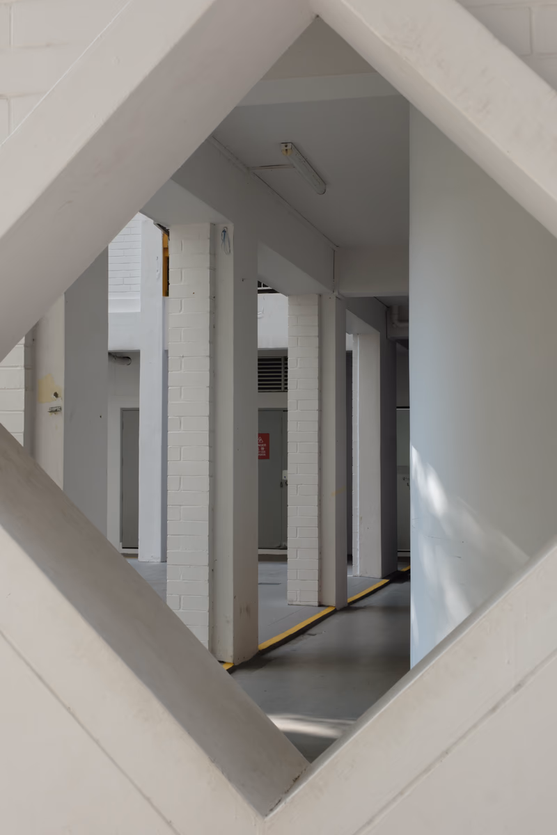 A photo of an industrial building interior with white columns and a yellow line.