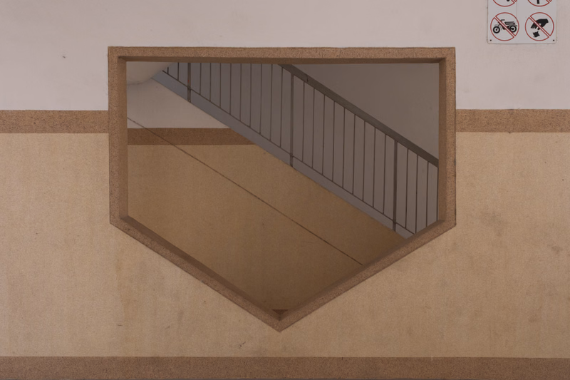 An open stairwell with a metal railing is visible within a beige and white interior space.