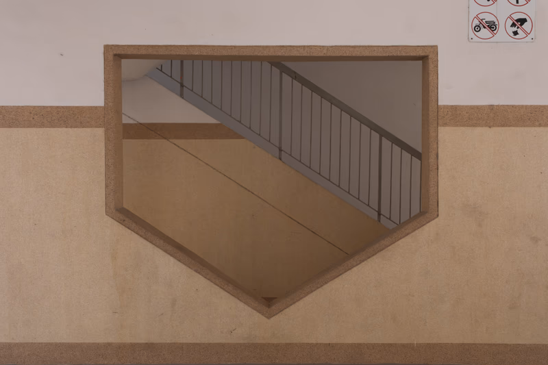 A photo of a window that reflects the interior of a building, showing stairs and railings.