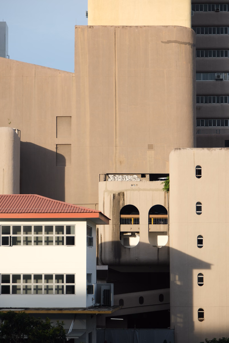 A composition of various modern concrete buildings with different architectural styles and heights under a bright sky.