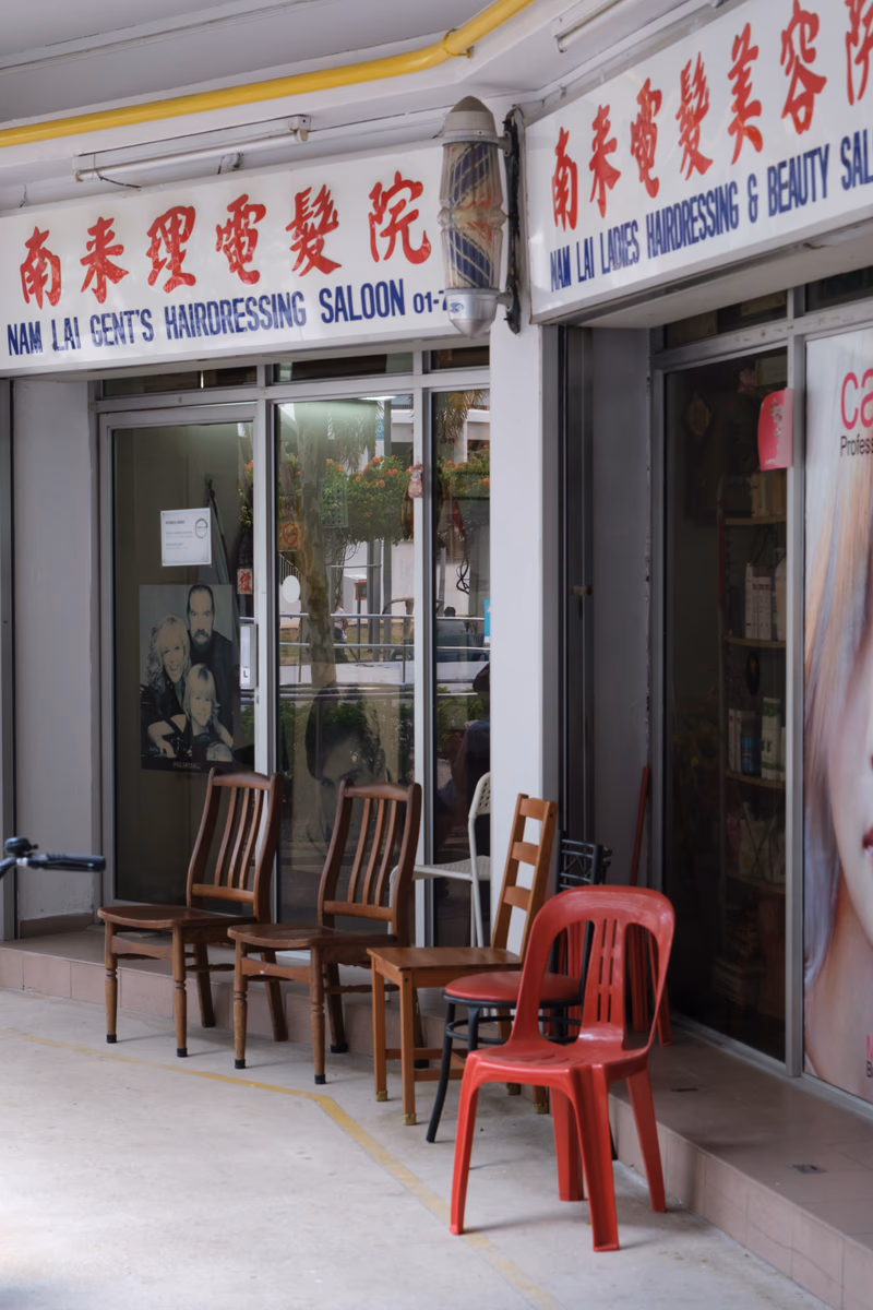 A photo of a salon with a sign that says 'NAN JI TEXT HAIR DRESSING SALON' and a row of chairs outside.