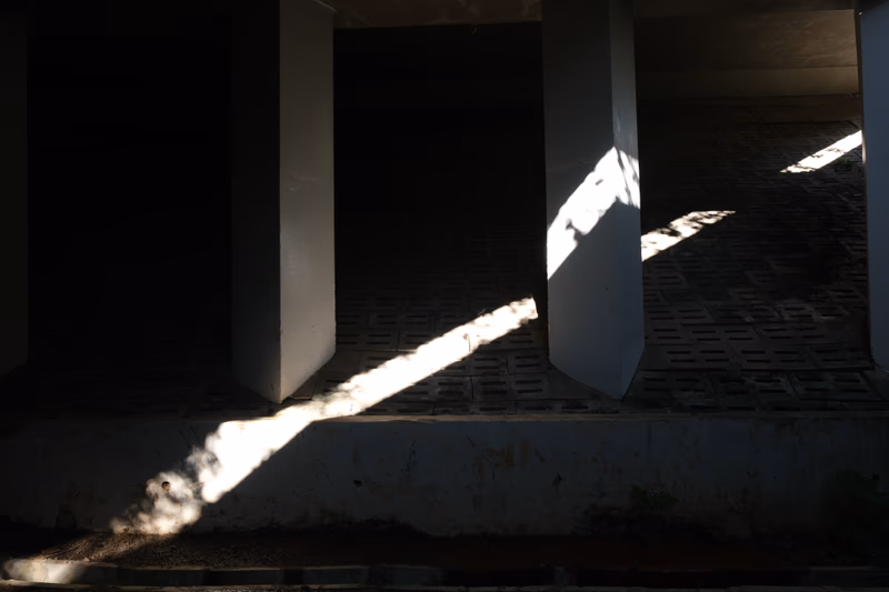 A photograph of a column under a light source casting shadows.