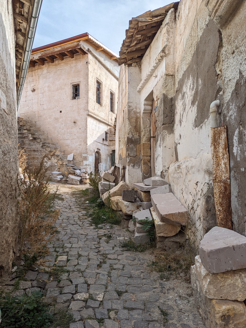 A narrow, cobbled alleyway runs between old stone buildings with weathered walls and exposed wooden beams.