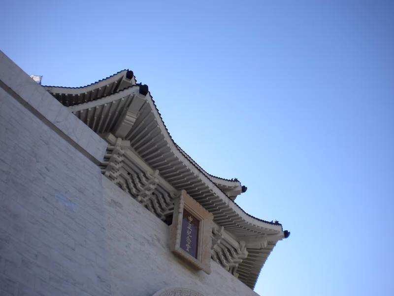 A traditional East Asian-style building facade with intricate roof details and a small window with a plaque