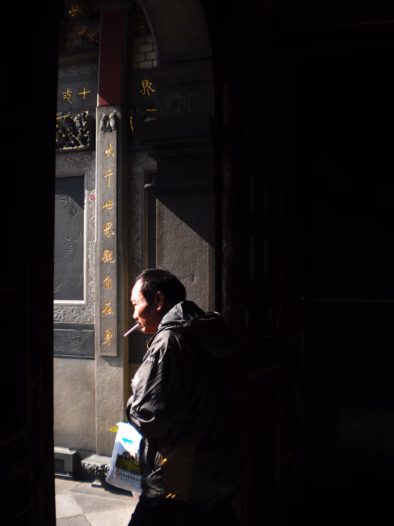 A man walking through a dimly lit corridor with a sign in Chinese characters and a beam of light illuminating his face.