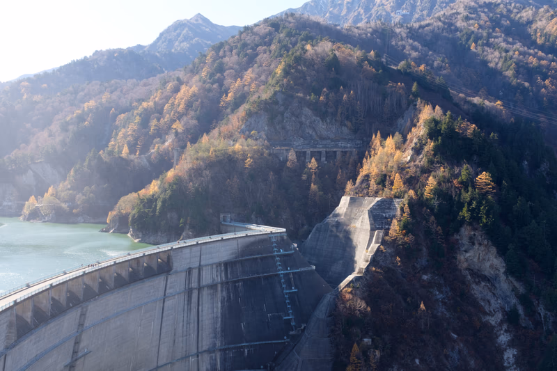 A dam in a mountainous area with trees and water