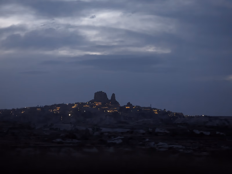 A photo of a city at night with a prominent hill in the background