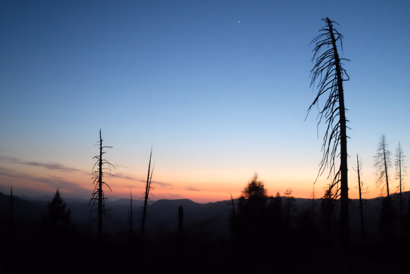 A beautiful sunset over a mountain range with a starry sky
