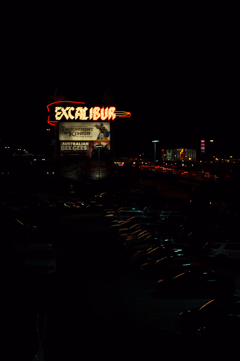 A large illuminated sign for "EXCALIBUR" is visible at night, with parking lots and city lights in the background.