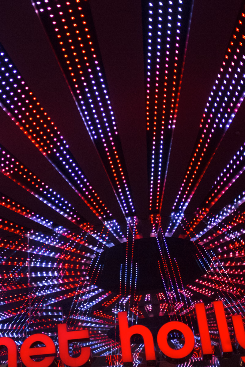 A vibrant interior shot of a disco or club featuring numerous bright red and blue lights shining down onto a dance floor, with the text "net holly" visible at the bottom.