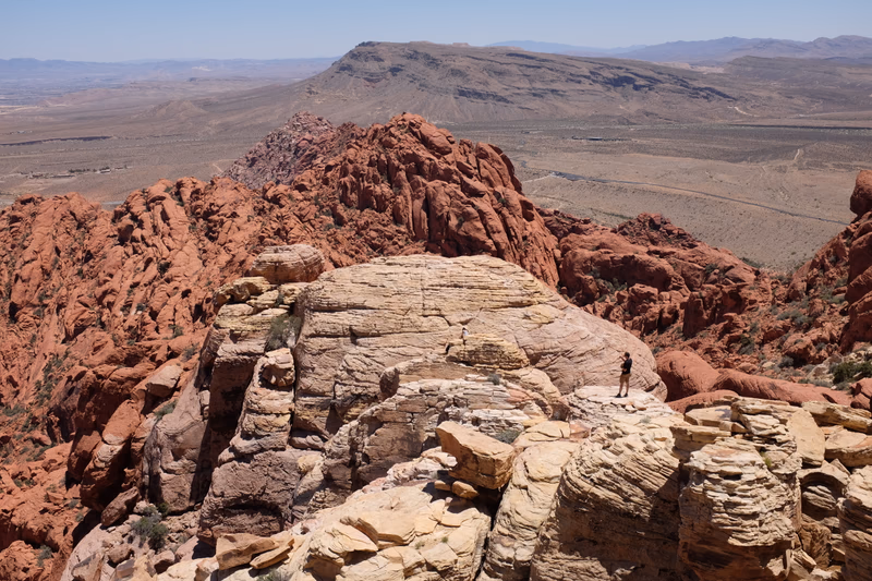 A person standing on a rocky cliff overlooking a vast desert landscape.