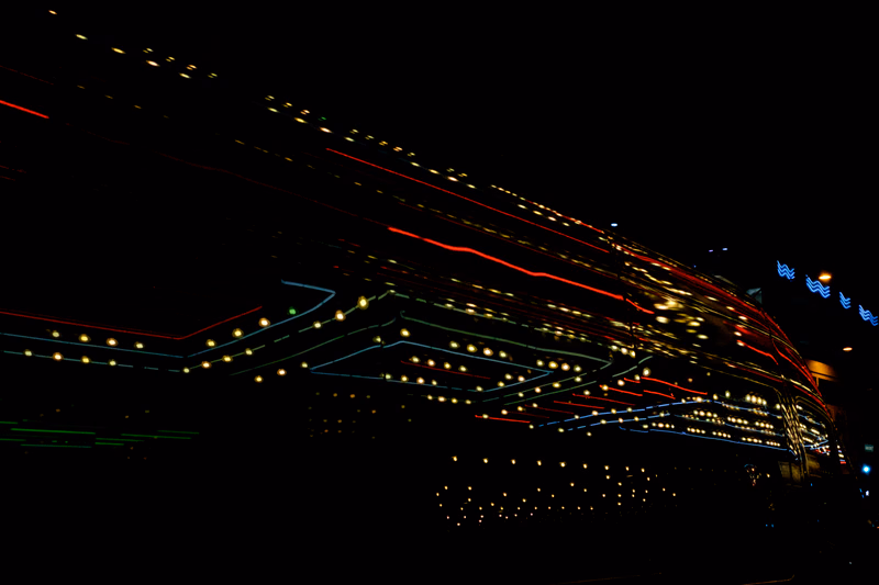 Long exposure photograph capturing streaks of red and white light trails from moving traffic against a dark night sky.