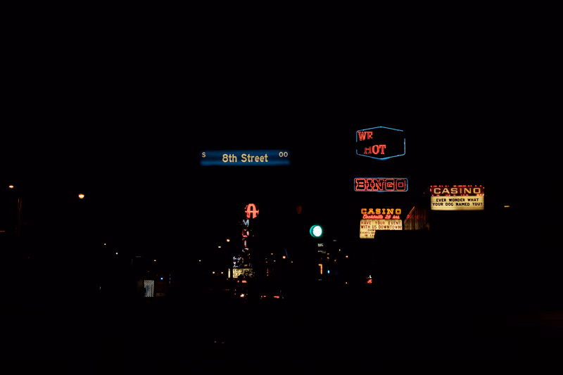 A nighttime street scene with illuminated signs and a bus stop.